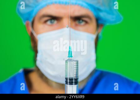 Le médecin tient une seringue de giclage avec des médicaments. Vaccination et immunisation. Le médecin en uniforme tient la seringue avec le vaccin. Médecin masculin en chirurgie Banque D'Images