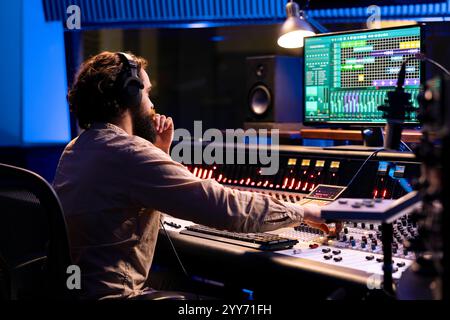 Expert audio opérant sur pupitre de commande avec faders motorisés et console de mixage en studio professionnel, utilisant des curseurs et des boutons pour traiter les sons. Ingénieur musical producteur enregistrant des pistes. Banque D'Images