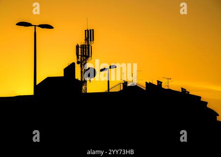 Les toits des bâtiments avec de nombreuses antennes dans une grande ville au coucher du soleil font des silhouettes Banque D'Images