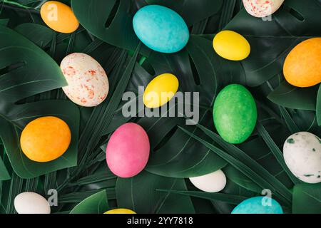 Fond de nature de Pâques. Palmier tropical vert et feuilles de monstera avec des œufs de Pâques. Composition de jungle ou de forêt abstraite de printemps minimale. Banque D'Images