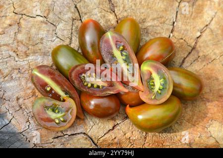 Tomates mûres rayées vert-rouge avec une pointe pointue, appartenant à la classe des tomates raisins. Concept de culture de variétés inhabituelles de tomates. Banque D'Images