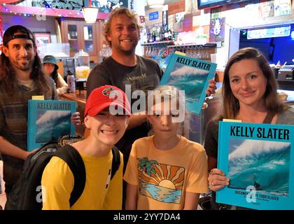 Cocoa Beach, comté de Brevard, Floride, États-Unis. 19 décembre 2024. Kelly Slater, 11 fois champion du monde de surf, et le plus grand surfeur du monde est retourné dans sa ville natale de Cocoa Beach pour un événement de signature de livre avec son photographe Todd Glaser. Des centaines de personnes ont fait la queue sur le trottoir devant Café Surfinista sur Orlando Avenue pour l'événement de 17 h, certaines arrivant dès 13 h 30. Slater a pris le temps de parler et d'échanger des histoires de surf avec chacun, ainsi qu'avec Glaser avant de signer personnellement leur livre. Le troisième livre de Slater, s'appelle une vie de vagues. Crédit Julian Leek / Alamy Live News Banque D'Images