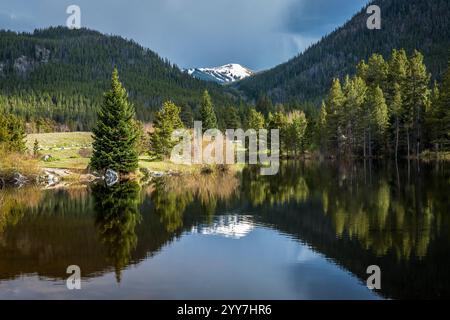 Les eaux claires de l'étang Gulch Pond reflètent les superbes montagnes Rocheuses sous un ciel nuageux, mettant en valeur la nature estivale sereine de Frisco. Banque D'Images