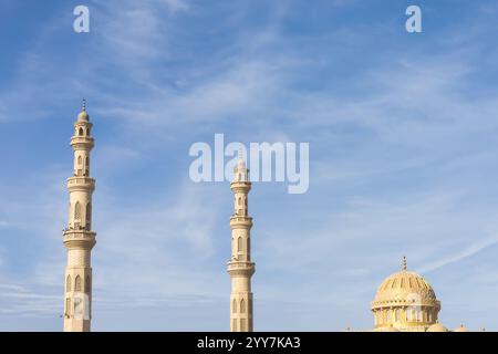 Capturant la beauté sereine des minarets et du dôme d'une mosquée sur un ciel bleu clair, cette image met en valeur l'architecture islamique Banque D'Images