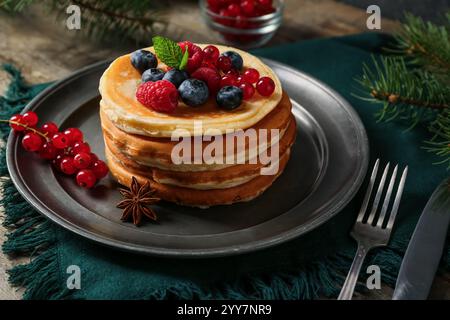 Assiette de crêpes sucrées avec des baies et branche d'arbre de Noël sur fond en bois Banque D'Images