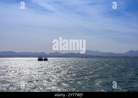 Vue imprenable sur un océan tranquille sous un ciel vaste et clair avec des silhouettes montagneuses lointaines Banque D'Images