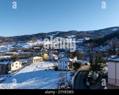 Vue aérienne capturant Morfasso, un charmant village niché dans les Apennins près de Piacenza, couvert de neige sous un ciel hivernal lumineux et ensoleillé Banque D'Images