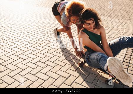 Deux copines ludiques s'amusant à skateboard ensemble dans un parc urbain. Capturez des moments joyeux et des activités de plein air. Banque D'Images