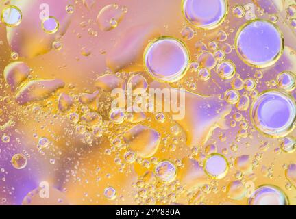 Composition abstraite vivante avec des bulles d'huile flottantes dans un dégradé de tons jaunes et violets. Idéal pour les designs créatifs, l'art moderne et la scienc Banque D'Images