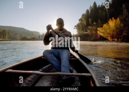 Man Serious Paddles Canoe dans Early Morning Light Banque D'Images
