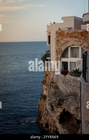 Une maison pittoresque en bord de mer perchée au bord d'une falaise, offrant une vue imprenable sur la mer Adriatique à Polignano a Mare, en Italie Banque D'Images