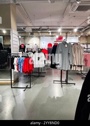 Kiev, Ukraine - 18 décembre 2024 : intérieur lumineux d'un magasin de vêtements moderne affichant des étagères de vêtements soigneusement arrangées. La photographie captu Banque D'Images
