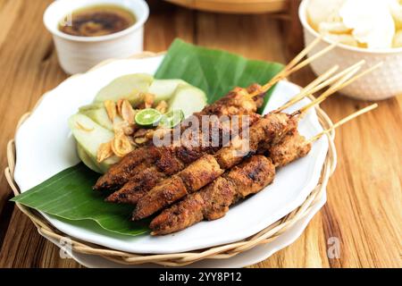 Gros plan Sate Ayam madura servi avec gâteau de riz pressé ou Lontong, sur fond de bois Banque D'Images