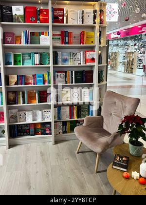 Kiev, Ukraine - 18 décembre 2024 : un coin accueillant dans une librairie dispose d'une chaise confortable, des étagères remplies de livres divers, et festif Banque D'Images