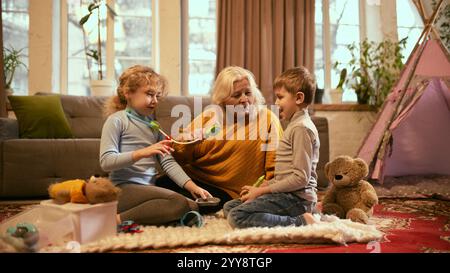 Grand-mère supervise les jeux de rôle des enfants en tant que médecins, encourageant l'apprentissage de la médecine et les bilans de santé par le jeu interactif. Banque D'Images