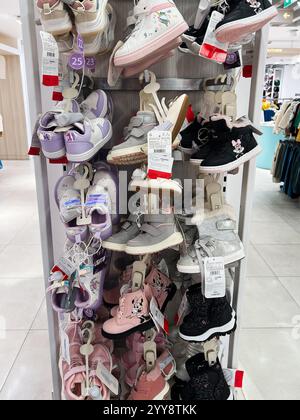 Kiev, Ukraine - 18 décembre 2024 : une vue rapprochée de chaussures assorties pour enfants disposées sur un présentoir dans un magasin, présentant divers modèles, col Banque D'Images