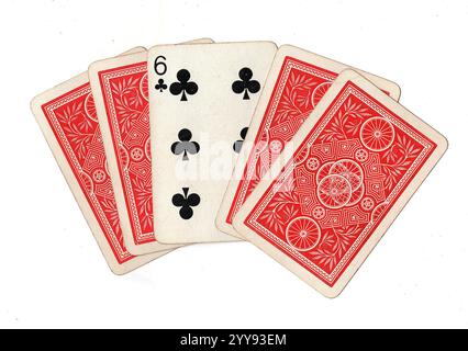 Une main de dos de cartes à jouer vintage avec le six de clubs révélé sur un fond blanc. Banque D'Images