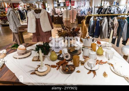 Une table élégante et inspirée de l'automne et un étalage de vêtements chic se trouvent dans une boutique tendance et accueillante. Paris, France - 24 octobre 2024 Banque D'Images