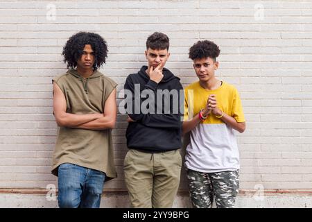 amis adolescents appuyés contre le mur de briques blanches Banque D'Images