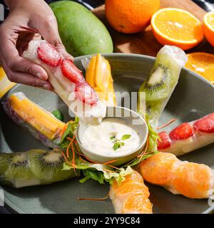 Un mélange coloré de rouleaux de printemps de fruits tropicaux faits avec des mangues fraîches, des fraises, des kiwis et des oranges, le tout délicatement enveloppé dans du riz translucide Banque D'Images