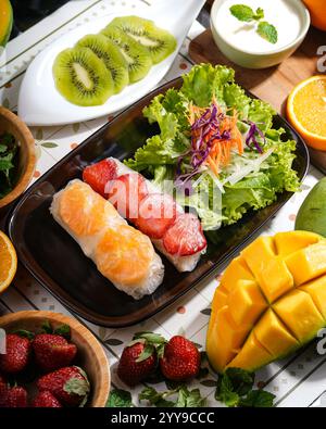 Un mélange coloré de rouleaux de printemps de fruits tropicaux faits avec des mangues fraîches, des fraises, des kiwis et des oranges, le tout délicatement enveloppé dans du riz translucide Banque D'Images