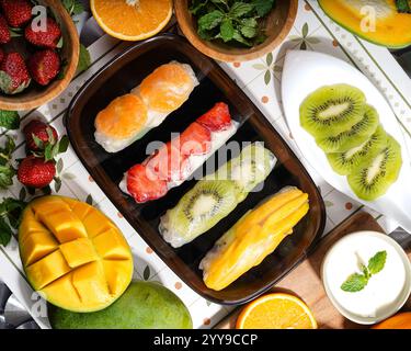 Un mélange coloré de rouleaux de printemps de fruits tropicaux faits avec des mangues fraîches, des fraises, des kiwis et des oranges, le tout délicatement enveloppé dans du riz translucide Banque D'Images