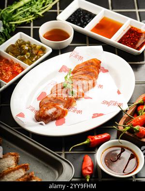 Poitrine de porc croustillante (style lechon kawali), parfaitement tranchée et servie sur un plateau avec une variété de sauces et condiments, accompagnée Banque D'Images