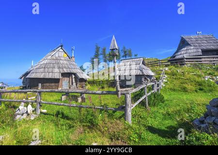 Pittoresques maisons en bois dispersées dans le paysage idyllique de velika planina, surplombant la vallée de la logarska dolina sous le chaud soleil d'été Banque D'Images