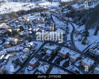 Vue aérienne capturant Morfasso, un charmant village niché dans les Apennins près de Piacenza, couvert de neige sous un ciel hivernal lumineux et ensoleillé Banque D'Images