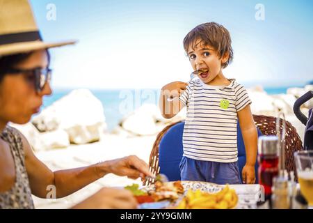 Mère et fils appréciant un délicieux repas ensemble dans un restaurant en bord de mer pendant leurs vacances d'été Banque D'Images