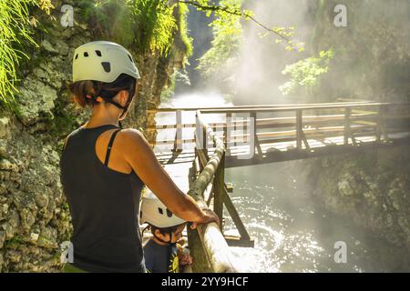 Mère et enfant portant des casques, profitant d'une vue imprenable sur le pont en bois sur la rivière radovna dans la gorge de vintgar près de Bled, slovénie Banque D'Images