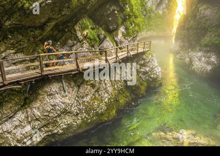 Touristes appréciant une promenade pittoresque le long du sentier en bois au-dessus de la rivière radovna émeraude, entouré par les falaises abruptes de la gorge vintgar Banque D'Images