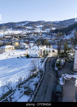 Vue aérienne capturant Morfasso, un charmant village niché dans les Apennins près de Piacenza, couvert de neige sous un ciel hivernal lumineux et ensoleillé Banque D'Images