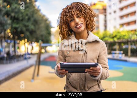 Portrait frontal d'une belle et heureuse femme latine tenant une tablette numérique travaillant à l'extérieur Banque D'Images