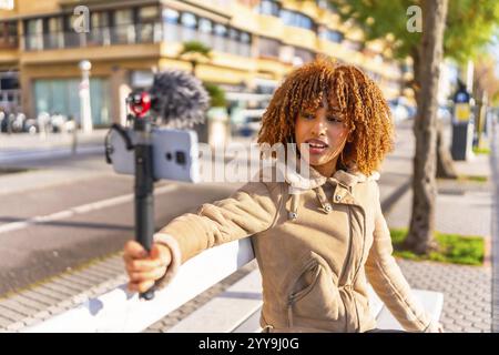 Beuty féminine latine et jeune vlogger en streaming en ligne assis sur les escaliers urbains dans une journée d'automne ensoleillée Banque D'Images