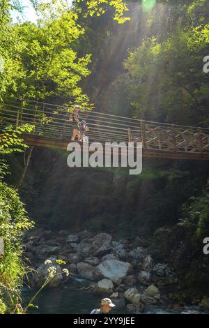 Mère et enfant marchant sur un pont suspendu dans la gorge de tolmin, slovénie, profitant de vacances d'été entourées par une nature luxuriante et les rayons du soleil Banque D'Images