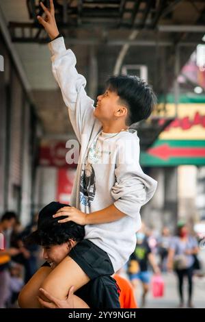 Les garçons philippins ont du mal à descendre leur balle d'un haut mur. Ils jouent dans les rues de China Town dans le quartier Binondo de Manille. Banque D'Images