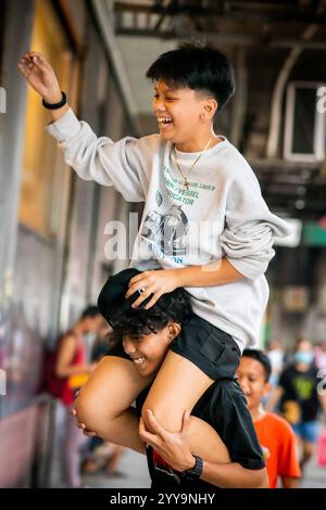 Les garçons philippins ont du mal à descendre leur balle d'un haut mur. Ils jouent dans les rues de China Town dans le quartier Binondo de Manille. Banque D'Images