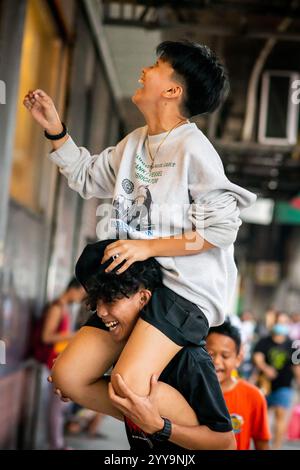 Les garçons philippins ont du mal à descendre leur balle d'un haut mur. Ils jouent dans les rues de China Town dans le quartier Binondo de Manille. Banque D'Images