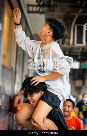 Les garçons philippins ont du mal à descendre leur balle d'un haut mur. Ils jouent dans les rues de China Town dans le quartier Binondo de Manille. Banque D'Images