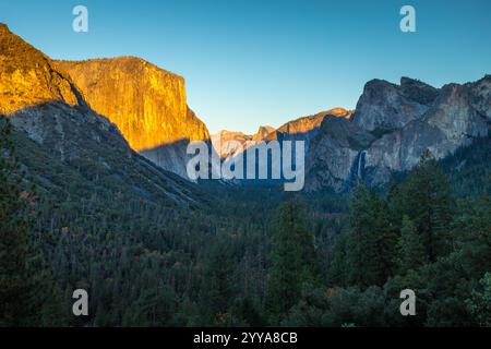 Le crépuscule jette une lumière chaude sur El Capitan tandis que les ombres se glissent à travers la vallée de Yosemite, mettant en valeur le paysage magnifique du comté de Mariposa. Banque D'Images