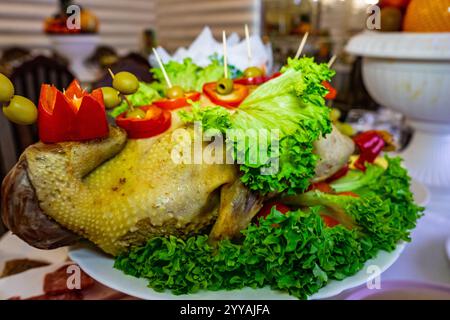 Un superbe plat de canard est habilement disposé sur un plateau, entouré de verts vibrants et de légumes colorés, mettant en valeur la créativité culinaire lors d'un festival Banque D'Images
