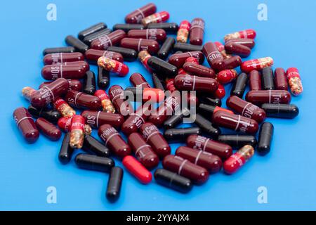Une vue rapprochée de capsules rouges et noires sur une surface bleue éclatante, Healthcare concepts. Banque D'Images