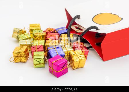 Boîtes-cadeaux miniatures vibrantes de différentes couleurs et rubans d'or débordant d'un sac à provisions élégant, célébrations, fêtes et occasions festives. Banque D'Images