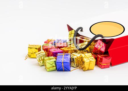 Boîtes-cadeaux miniatures vibrantes de différentes couleurs et rubans d'or débordant d'un sac à provisions élégant, célébrations, fêtes et occasions festives. Banque D'Images