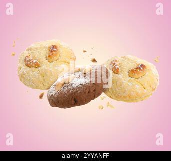 Biscuits savoureux avec des noix de cajou dans l'air sur fond rose Banque D'Images