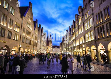 Münster, NRW, Allemagne, 20 décembre 2024. Le célèbre boulevard Prinzipalmarkt est fermé à la circulation et très fréquenté par les visiteurs. Münster (Muenster) et ses cinq marchés de Noël sont animés par des foules de visiteurs festifs de toute la NRW, ainsi que des pays-Bas et d'ailleurs ce soir. Des milliers de personnes affluent vers les marchés traditionnels du pittoresque centre-ville historique. Une sécurité renforcée est visible, les voies d'accès sont limitées, les espaces entre les rues et les marchés ont été bloqués avec des sacs de sable en acier ou en béton et d'autres mesures. Ce soir, une attaque a été menée à Magdebourg Christmas Banque D'Images