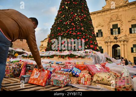 La Valette, Malte. 20 décembre 2024. Un homme place un cadeau de Noël lors d'un événement caritatif de don de cadeaux de Noël à des enfants dans le besoin à Castille Square à la Valette, Malte, le 20 décembre 2024. Crédit : Jonathan Borg/Xinhua/Alamy Live News Banque D'Images