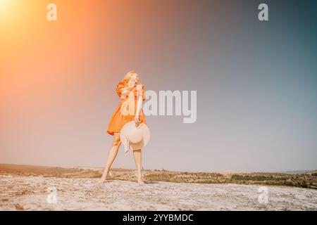 Femme dans une robe rouge debout sur un rocher avec ciel bleu Banque D'Images