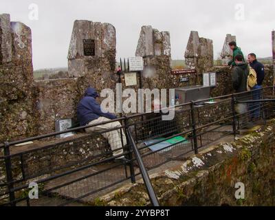 Les gens attendent pour embrasser le panneau de pierre de Blarney au château de Blarney, en Irlande Banque D'Images